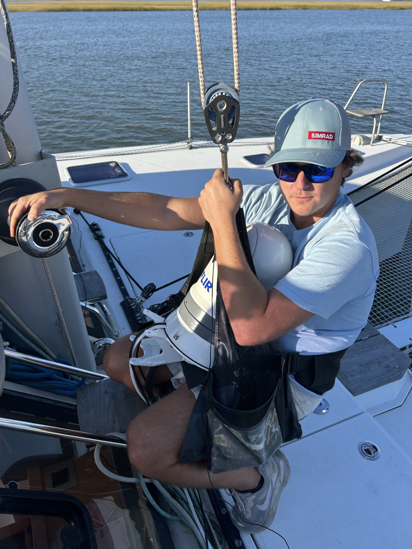Technician working aloft beside a mast-mounted FLIR thermal camera